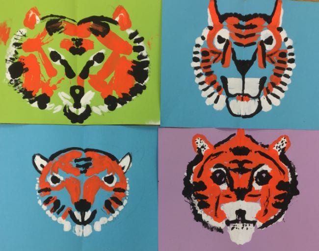 Symmetrical tiger faces printed with paint on colored backgrounds (Second Grade Art)