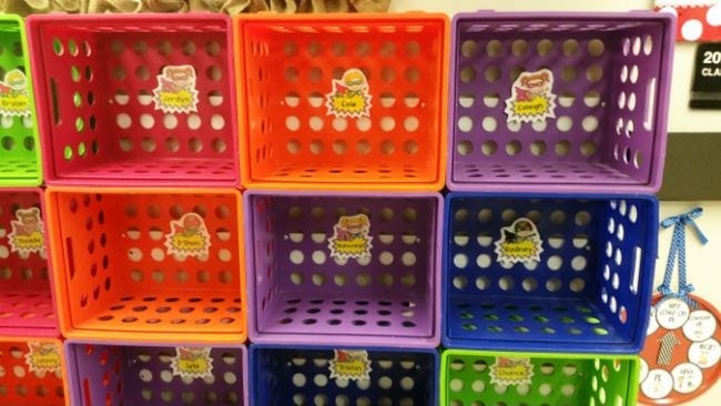 Colorful plastic crates stacked into classroom cubbies and labeled with student names