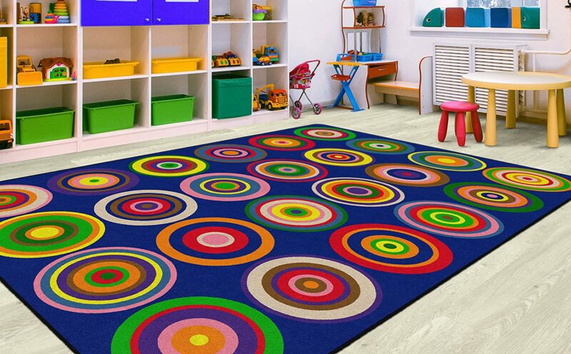 A blue rug with colorful circles on it as an example of classroom rugs.