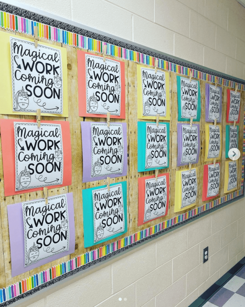 Bulletin board with large signs saying "Magical Work Coming Soon," held to the board by clothespins (Back-to-school bulletin board ideas)