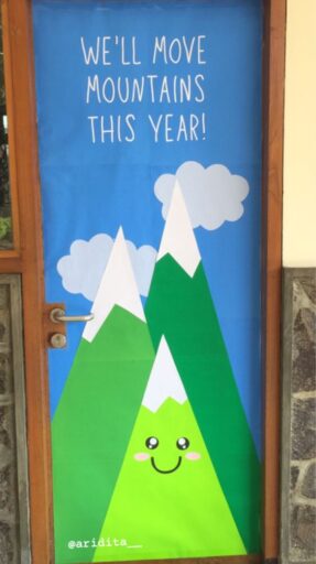 we'll move mountains this year classroom door with smiling mountains and a blue background