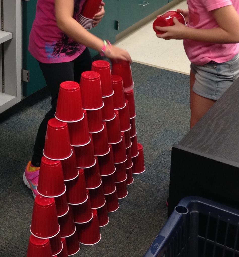 Two children stacking red solo cups to build a wall as a fun activity for teaching 3rd grade