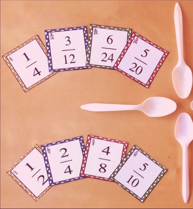 Fraction cards laid out with plastic spoons to play a fourth grade math game