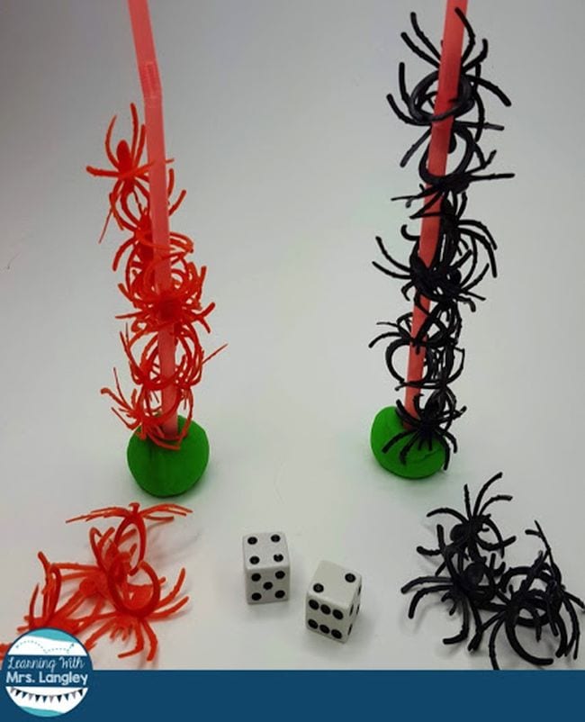 Two towers, one of red plastic spiders and one of black plastic spiders and a pair of die