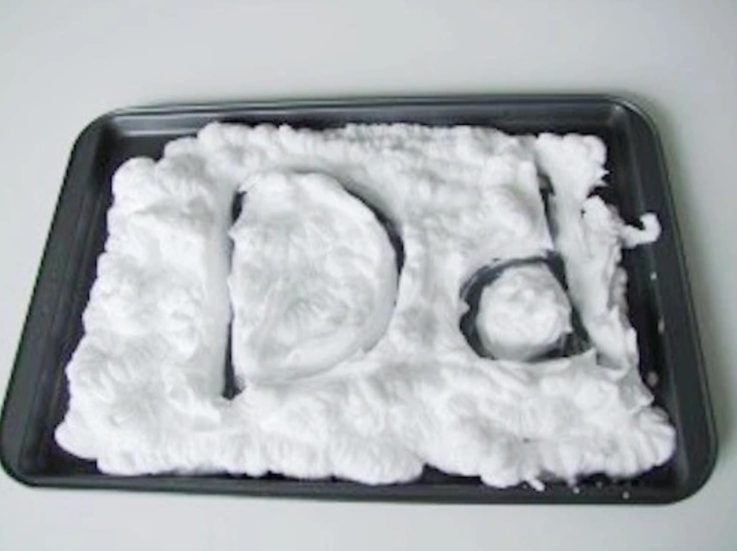 Upper case and lower case letter D written on a cookie sheet covered with shaving cream 
