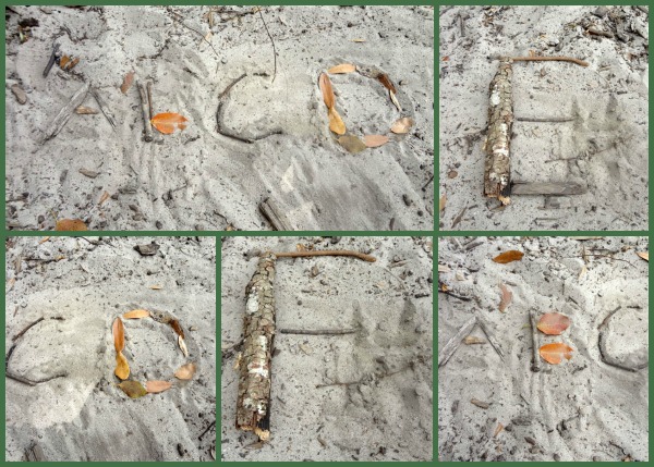 Letters written in the sand using sticks and leaves