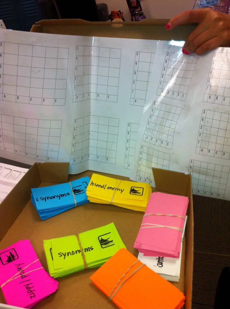 packs of synonym cards and grids in the background for a battleship-type game, an an example of activities on synonyms