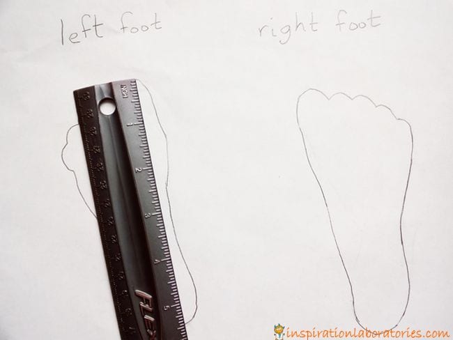 The outline of two feet on a white paper with a black ruler laid over one of the feet