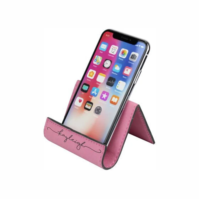 A leather phone stand has a name embroidered on it.