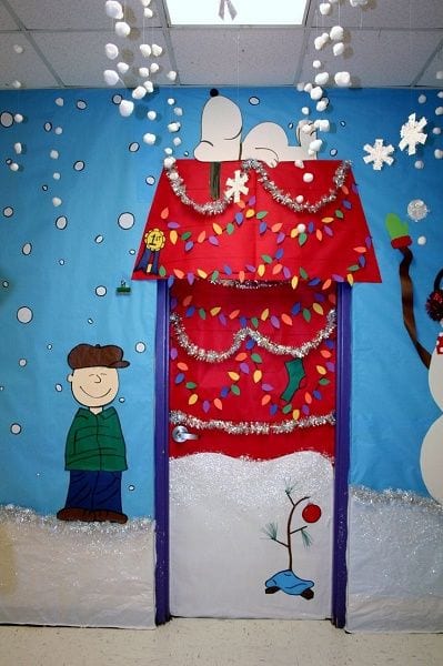 A classroom door has Snoopy's dog house on it decorated for Christmas.