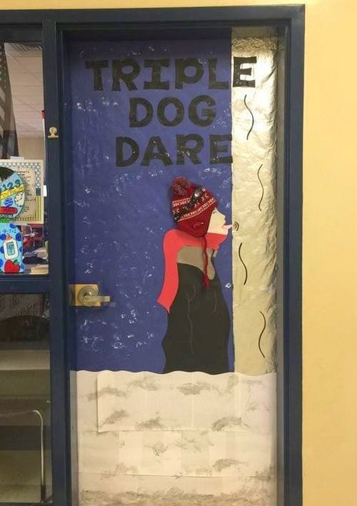 Classroom door decorated with a boy with his tongue stuck to a flagpole, with text reading Triple Dog Dare- holiday classroom doors