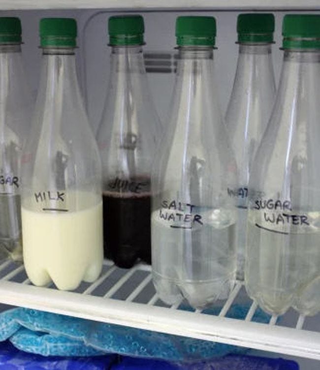 Clear bottles on a freezer shelf labeled milk, juice, salt water, water, and sugar water