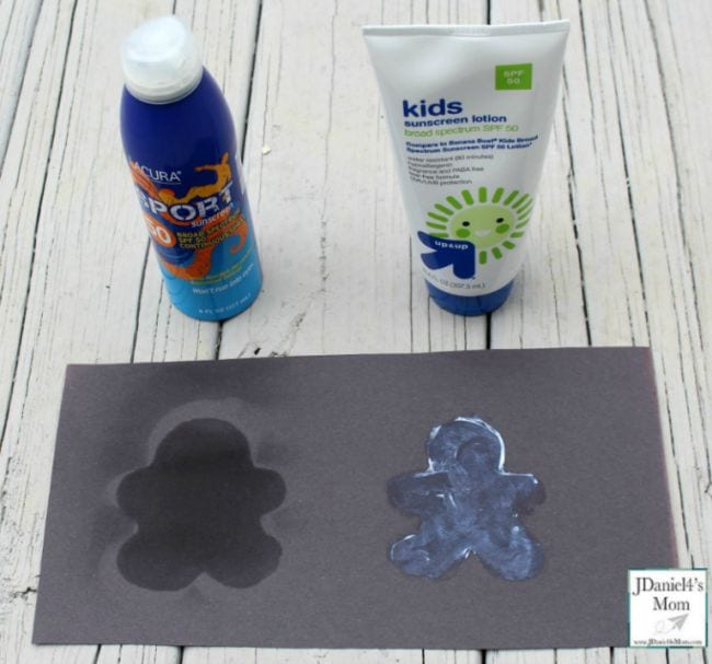Black construction paper with gingerbread man outlines covered in sunscreen, showing paper has faded except where protected by sunscreen