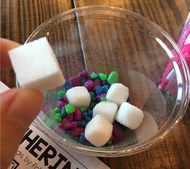 Plastic cup holding sugar cubes and smaller candies