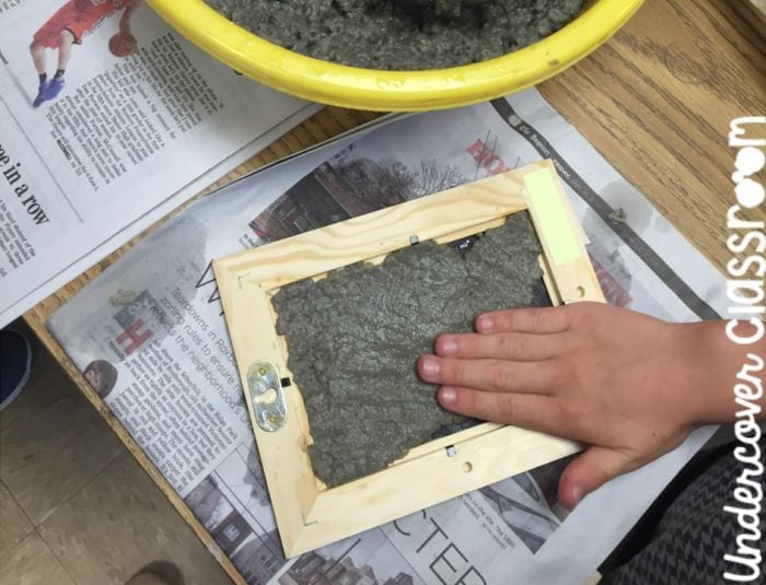 Science student making recycled paper using a wood frame covered in wire mesh