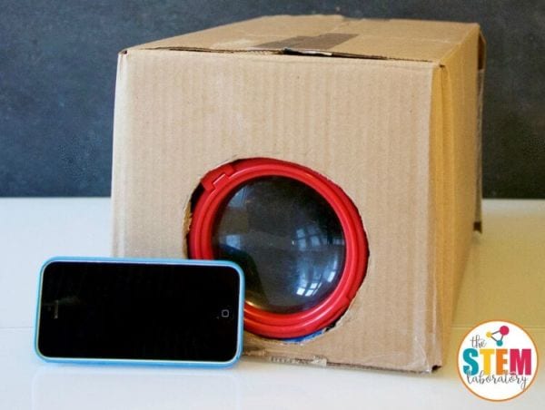 Cardboard box with a magnifying glass embedded in it, with a smart phone 