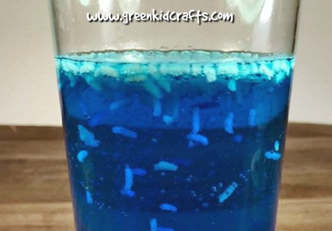 Glass of blue liquid with rice floating and moving in it