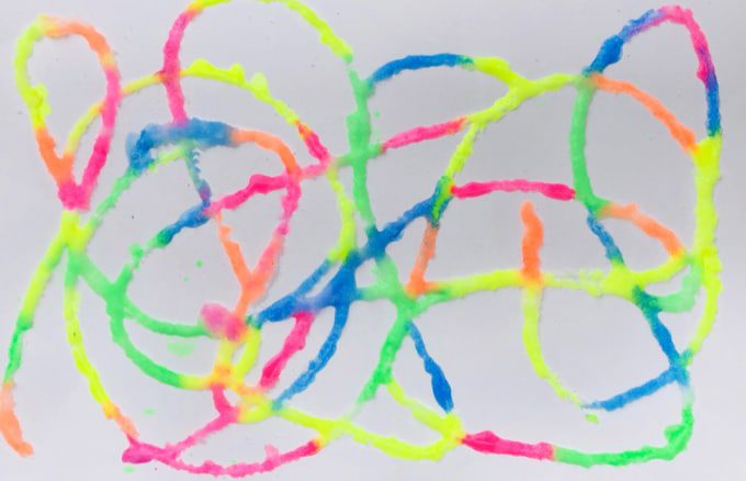 Brightly colored puffy paint is swirled across a paper.