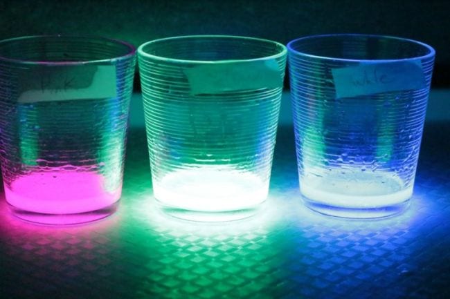 Three beakers filled with glowing liquid