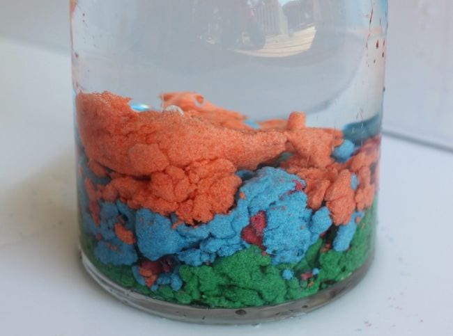 Colorful layers of hydrophobic sand in a jar of water