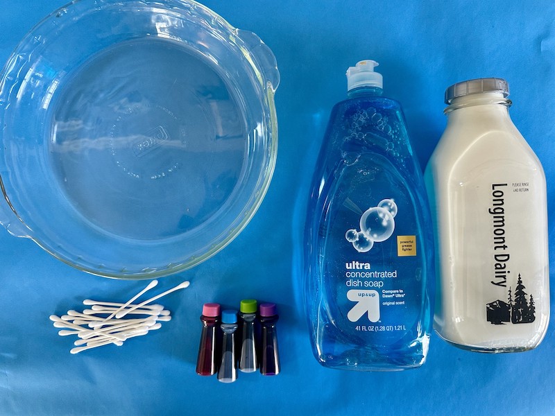 Milk, dish soap, food coloring, and cotton swabs for magic milk experiment