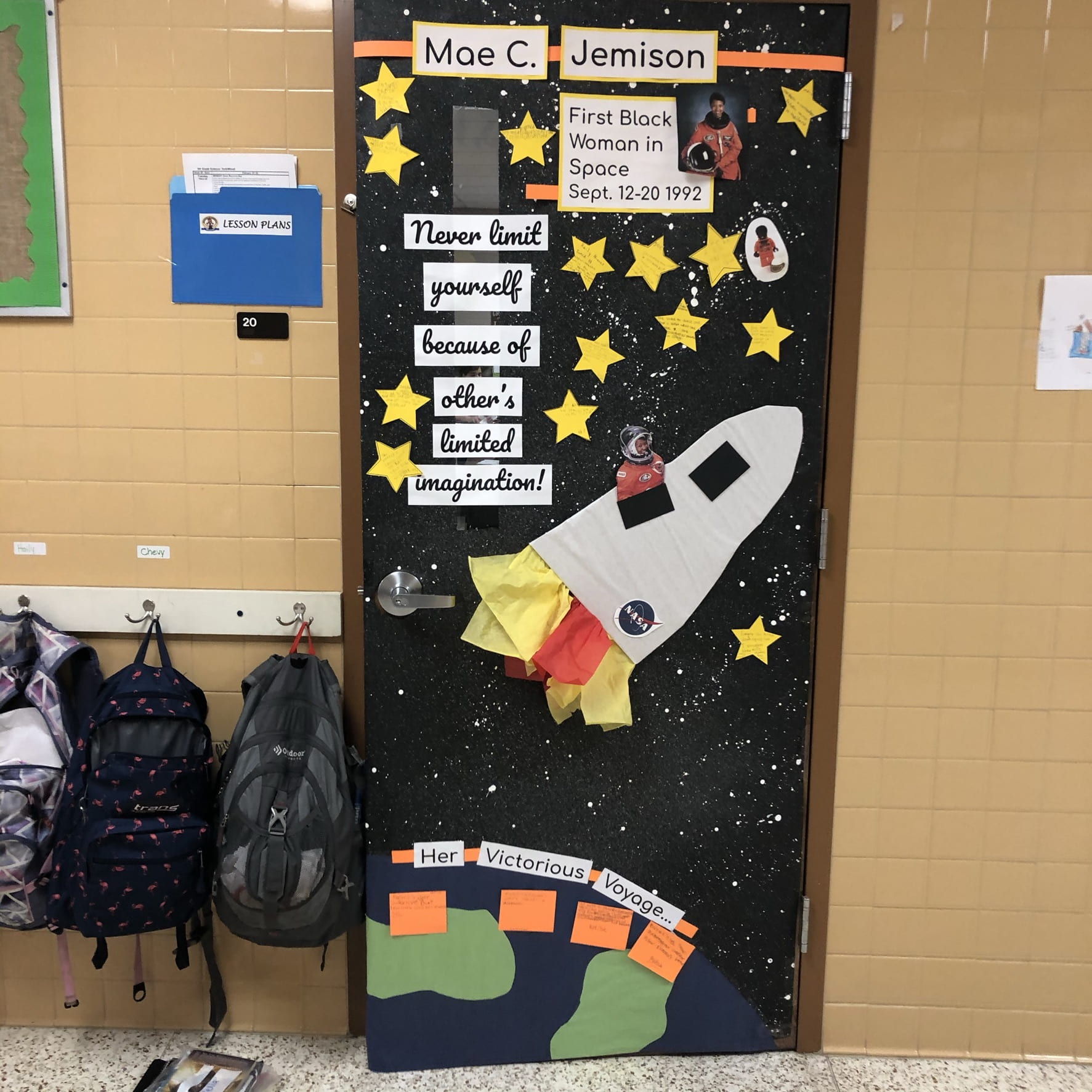 A classroom door has a rocketship on it shooting off from Earth. It says Mae C. Jemison. Text reads 