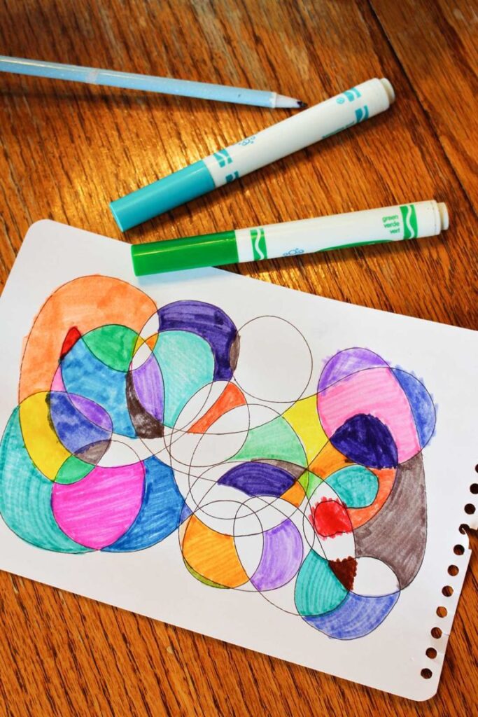 A piece of paper has intertwining circles that are colored with markers.