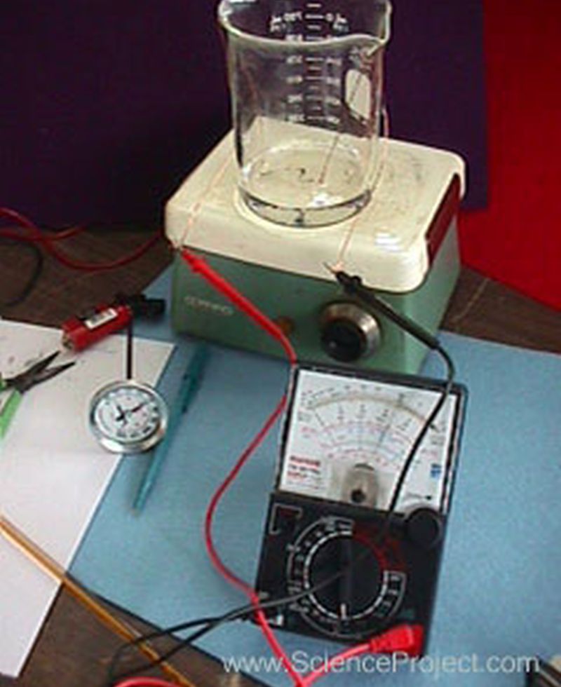 A beaker with a tungsten rod, connected to a multimeter