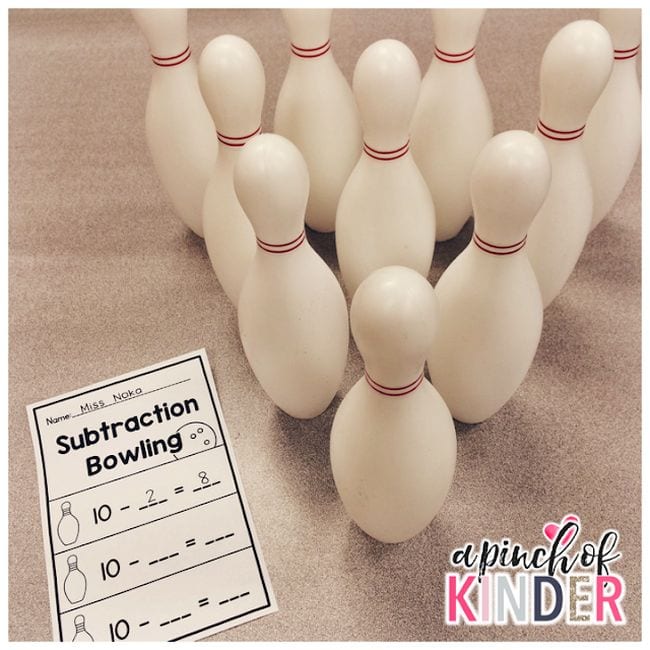 A subtraction bowling worksheet in front of a set of bowling pins