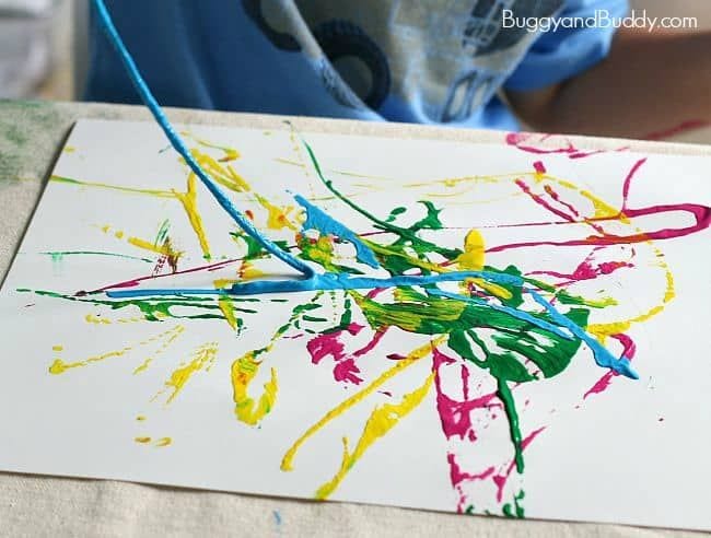 Paint is splattered on a white paper in this example of kindergarten art projects.