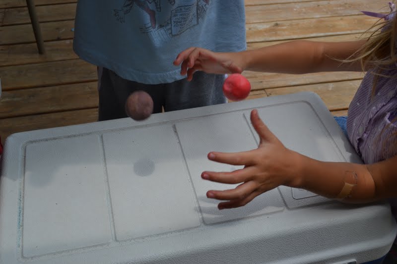 Two children are shown (without faces) bouncing balls on a white table