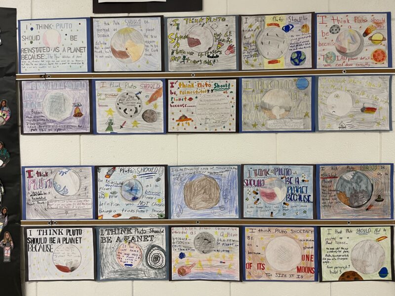 Bulletin board featuring student designed posters about the planet Pluto.