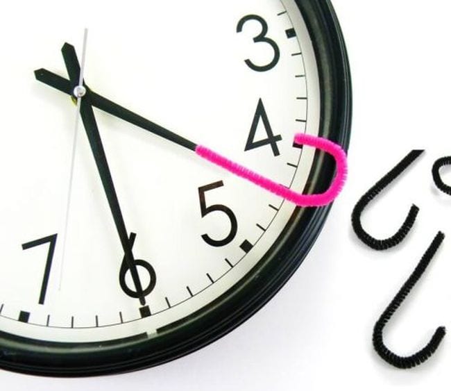 Analog clock with a pink pipe cleaner hook attached to the hour hand in this example of telling time games.