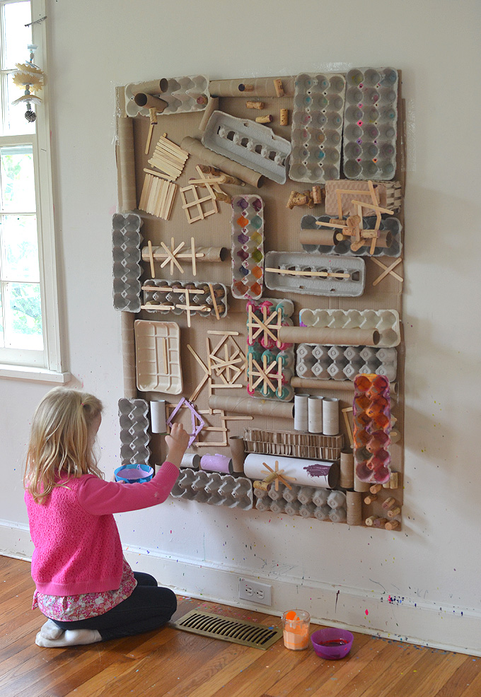 A colorful art wall created from recycled materials like cardboard, egg cartons, paper towel tubes and craft sticks