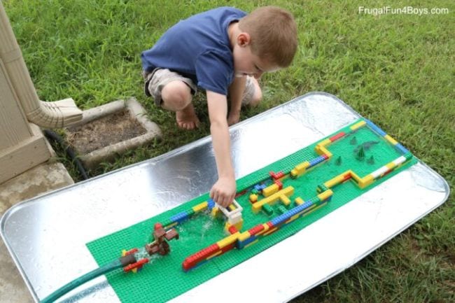 Child playing with a watercourse built of LEGO bricks