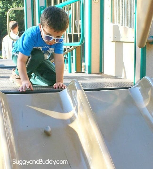 Child sending an object down a playground slide