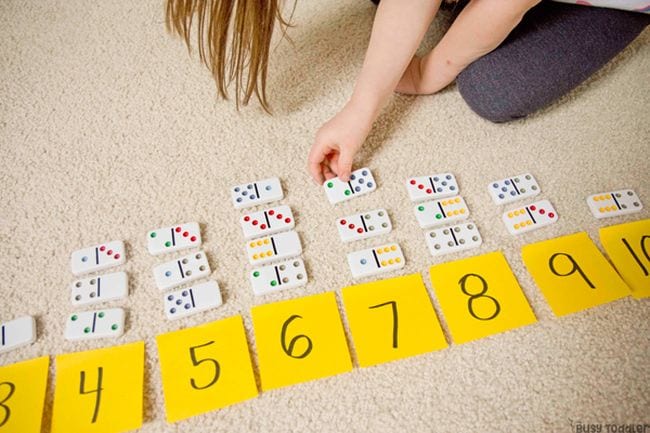 Child lining up dominos based on the numbers they add up to