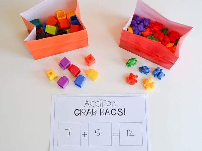 Two paper bags with small toys inside each. A number have been pulled out each bag, and a paper below shows the addition equation they represent