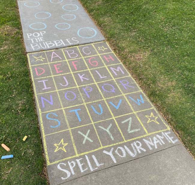 An obstacle course for kids drawn with chalk on a sidewalk, starting with a grid of letters where kids must jump to spell out their name in this example of obstacle courses for kids