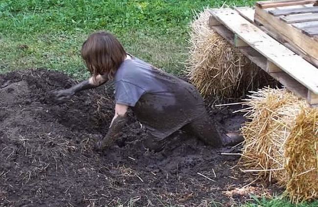 Child crawling through the mud underneath planks laid across hay bales in this example of obstacle courses for kids