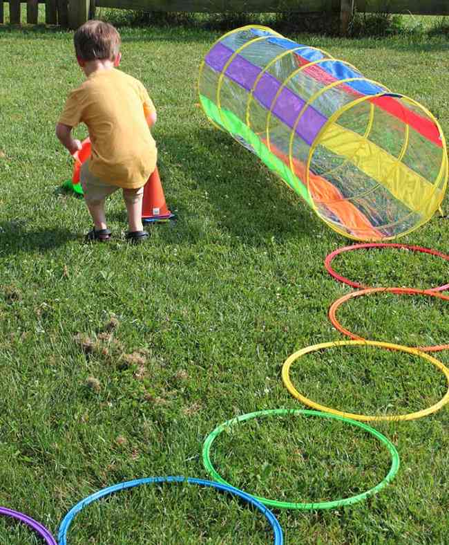 Child setting up colorful plastic cones as part of a rainbow-themed obstacle course in this example of obstacle courses for kids