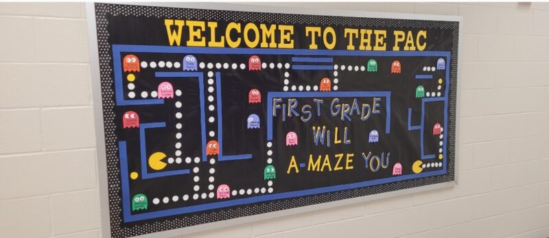A bulletin board is designed to look like a Pac-Man screen. Letters read Welcome to the First Grade.