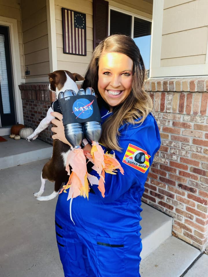 Teacher dressed as an astronaut, with her dog dressed as a rocket