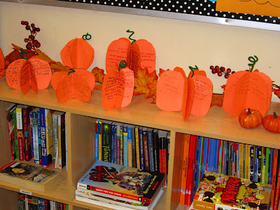 A line of colorful construction paper pumpkins on a bookshelf