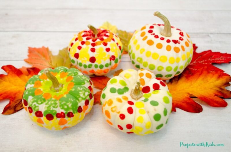 Fall art projects can include real pumpkins. This one shows four white pumpkins that have been painted with q-tips.