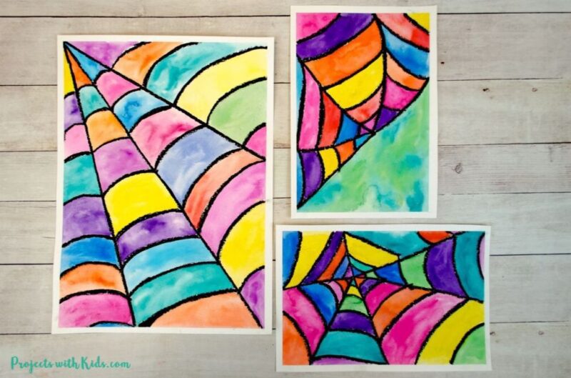 Fall art projects can include watercolor projects like this one. Three pieces of paper are divided into a web with black and each section of the web is colored in a different color using watercolor paints.