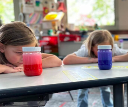 Two students stare at a calm down jar on their desks for a social emotional learning activity