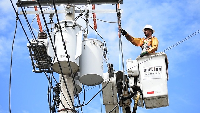 An electrician works on power lines from a cherry picker bucket