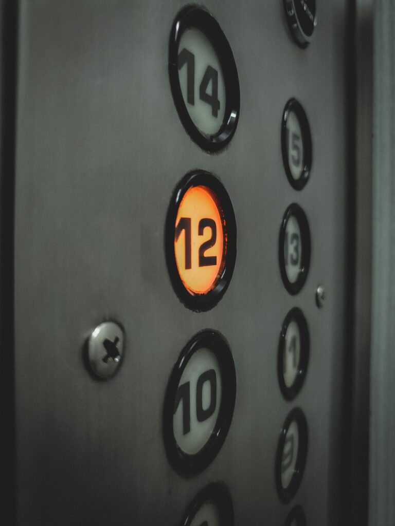 Closeup of elevator button panel, with the number 12 lit up