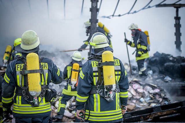 A group of firefighters face a burnt out structure.